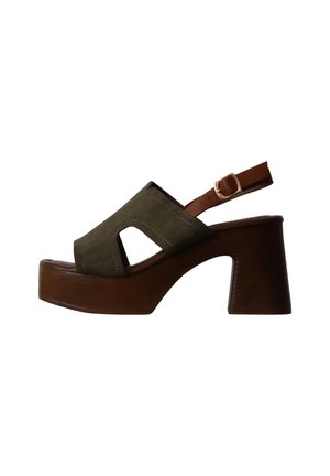 Sandale à talon marron à bout ouvert avec dessus en daim vert olive et bride ajustable à la cheville avec boucle dorée sur fond blanc.