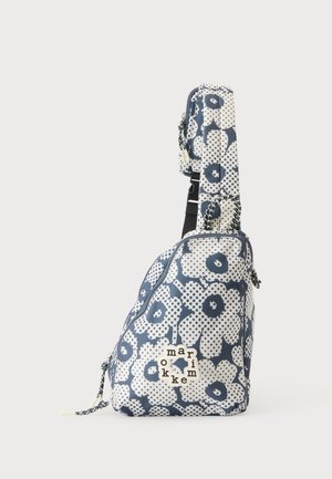 Petit sac bandoulière avec motif floral bleu marine et blanc et sangle réglable, avec une étiquette de marque tissée sur la poche avant.