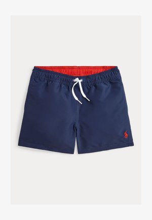 Tumšo zilo peldbikses ar elastīgu sarkanu jostu, baltu saiteņu un mazu sarkanu logo apakšējā kreisajā pusē. Gluda auduma tekstūra.