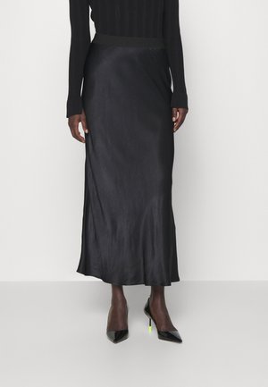 Sort midinederdel kombineret med sort ribbet langærmet top og sorte spidse høje hæle med neongule hælkapsler.