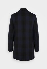 Manteau à carreaux bleu marine et noir, doté d'une coupe ajustée, d'un col cranté, de poignets à trois boutons et d'une unique fente à l'arrière.