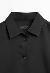 Black button-up shirt with a structured collar, featuring a smooth, matte texture and four front buttons. Label reads "Massimo Dutti."