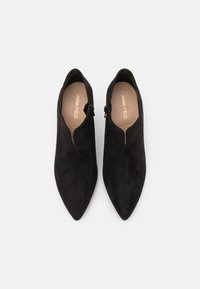 Botines de ante negro hasta el tobillo con punta afilada y cremalleras laterales. El interior presenta la marca "ANNA FIELD" en un color claro. Textura suave.