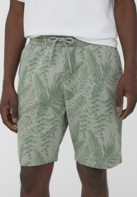 Pantaloni corti verdi con un motivo a foglie, vita elastica e cordino regolabile. Realizzati in tessuto morbido con una vestibilità comoda.