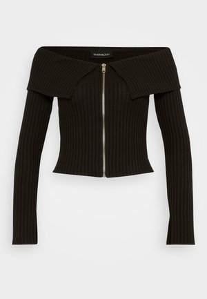 Top nero a coste scivolato sulle spalle con maniche lunghe e una cerniera frontale. Presenta un colletto strutturato e un design aderente.