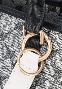 Zwart-wit gestreepte stoffen tas met gouden hardware, voorzien van een dubbele ringbevestiging. Textuur van zwart hengsel met een witte accent.