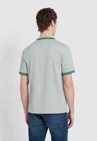 Polo shirt grigio a maniche corte con colletto e maniche a coste verdi, caratterizzato da una vestibilità comoda e una consistenza liscia simile al cotone.