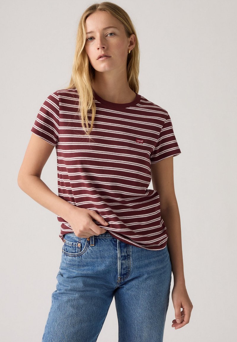 T-shirt rayé bordeaux et blanc ; manches courtes, col rond, tissu doux ; petit logo Levi's sur la poitrine ; associé à un jean bleu.
