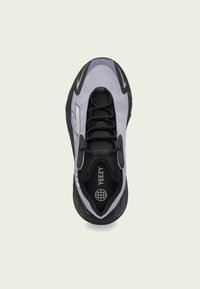 Sapatilha preta e cinza com um cabedal suave e texturizado, sistema de atacadores à frente e uma marcação proeminente da Yeezy na palmilha e na lateral.