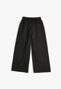 Zwarte wijde broek met een elastische tailleband, gemaakt van zachte stof, met een gladde textuur en een minimalistisch ontwerp.