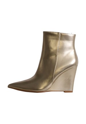Bottine dorée brillante avec bout pointu et talon compensé, finition cuir lisse, détail de couture latérale et semelle basse.