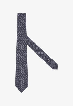 Námornícky modrá kravata s bielym a červeným abstraktným vzorom, vyrobená z hladkej tkaniny. Má špicatý koniec a na zadnej strane je označenie s logom.