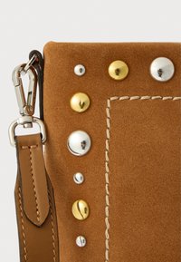 Brun semsket veske med metallnagler i sølv, gull og bronse. Har en lys lærreim med synlige sting og hardware detaljer.