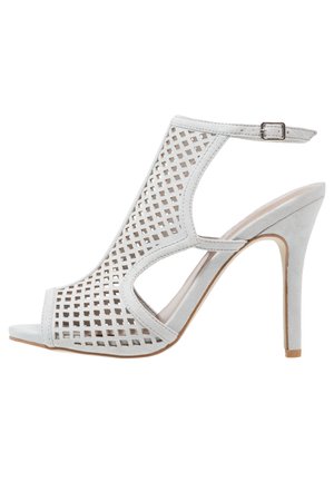 Hvid højhælet sandal med gitterudskæringer, åben tå, ankelrem med spænde og stiletthæl.