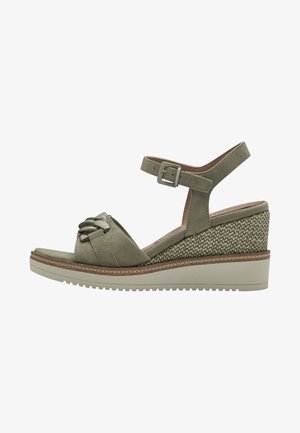 Olive green wedge sandals with a knotted front design, adjustable ankle strap, and textured woven heel. Rubber sole with light tread.