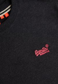 Mørkegrå striktrøje med rødt broderet "SuperDry"-logo og japanske tegn nær brystet, med ribstrikket rund halsudskæring og størrelsesmærker.