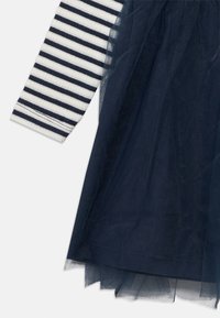 Μπλουζάκι με μακριά μανίκια σε ναυτικό μπλε και λευκές ρίγες, συνδυασμένο με διαφανές τούλινο στρώμα φούστας σε ναυτικό μπλε χρώμα με πολυεπίπεδα άκρα.