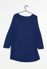 Granatowy sweter z długim rękawem, dziany, z dekoltem w łódkę, wiszący na czarnym wieszaku drucianym na białym tle.