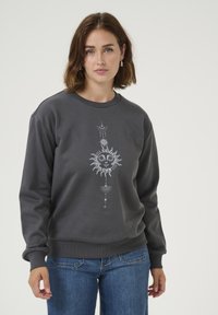 Sweat-shirt gris en tissu doux, avec un graphique central représentant un soleil avec des détails élaborés. Il a des poignets côtelés et un col rond classique.