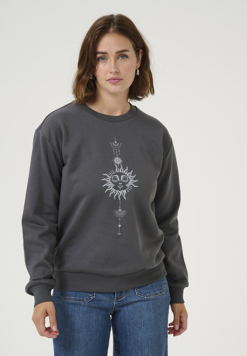 Sweat-shirt gris en tissu doux, avec un graphique central représentant un soleil avec des détails élaborés. Il a des poignets côtelés et un col rond classique.