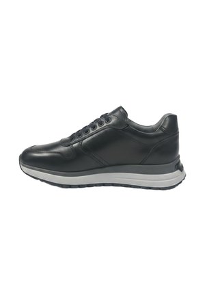 Zwarte leren sneaker met zwarte veters en een dikke witte en zwarte rubberen zool, zijaanzicht op een witte achtergrond.