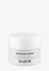 Crème d'équilibre dans un pot en verre transparent avec un couvercle blanc. Présente un texte noir à l'avant : "CRÈME D'ÉQUILIBRE" et "BABOR". Design simple.