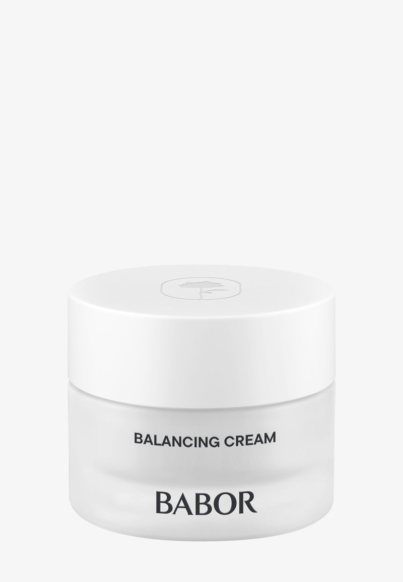 Crème d'équilibre dans un pot en verre transparent avec un couvercle blanc. Présente un texte noir à l'avant : "CRÈME D'ÉQUILIBRE" et "BABOR". Design simple.