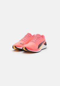 Zapatillas de running ligeras en malla rosa brillante con acentos negros y una suela amarilla. Cuentan con cordones tradicionales y una suela acolchada.