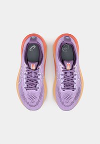 Zapatillas deportivas moradas con parte superior de malla, puntera reforzada y suela exterior degradada en tonos naranjas. Incluyen cordones grises y logotipo en la lengüeta.