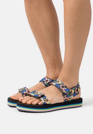 Sandalias con estampado floral y correas ajustables, diseño en azul y multicolores, suela negra gruesa con acentos de rayas de colores del arcoíris.