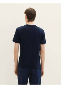 Námořnická modrá pánská tričko s kulatým výstřihem vyrobené z měkké látky, s krátkými rukávy a rovním lemem. Minimalistický design bez viditelných vzorů nebo log.