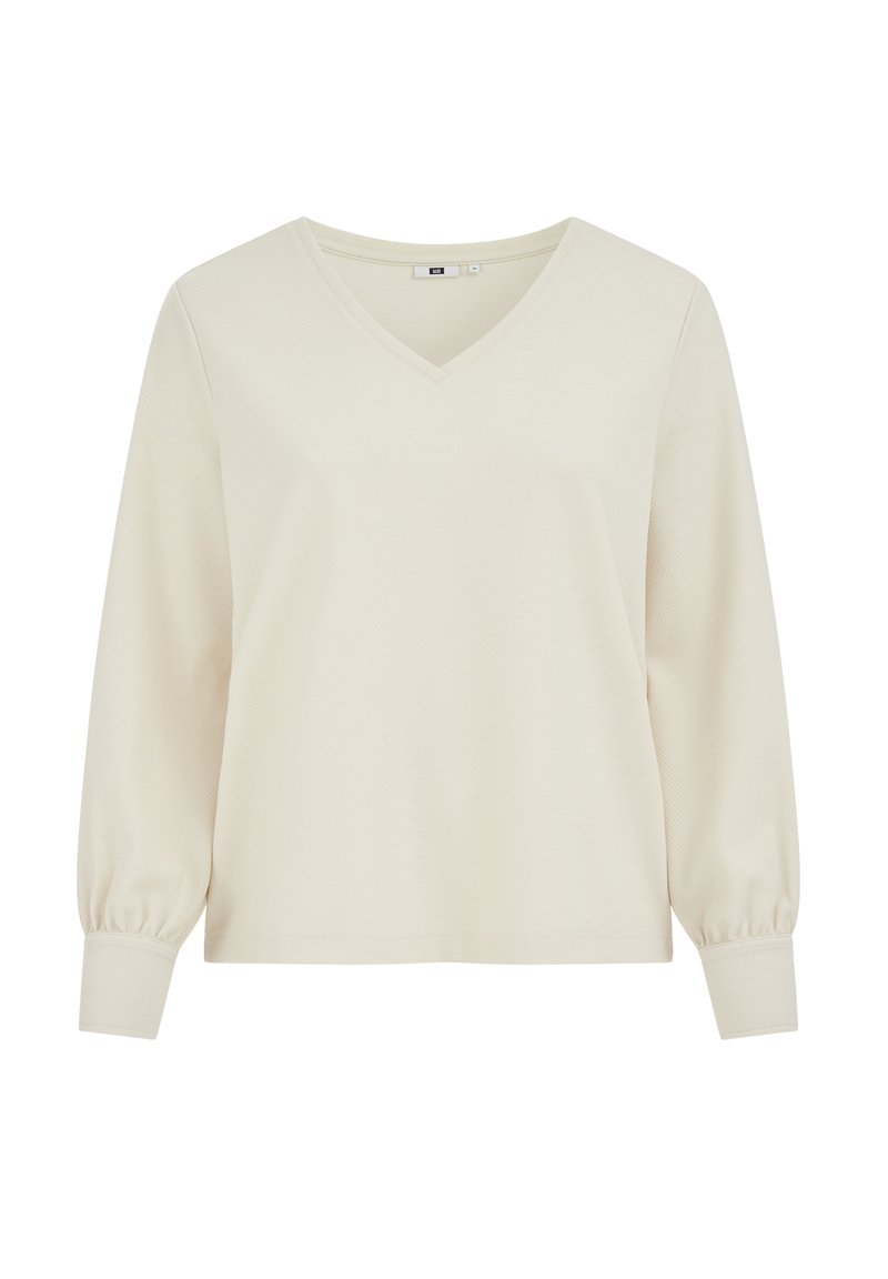 V-nyakú, hosszú ujjú felső világos krémszínben, texturált anyagból, enyhén pöndörödő ujjakkal és testhez simuló mandzsettákkal a kényelmes viseletért.