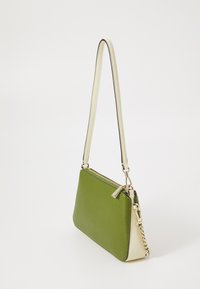 Piccola borsa a tracolla rettangolare in pelle verde e crema, con zip dorata e dettagli in catena, su sfondo bianco.