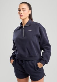 Tummansininen vetoketjuhuppari ribbineuloksilla varustetuilla hihoilla ja helmalla, jossa on "New York" -kirjonta rinnassa. Yhdistetty samanlaisisiin shortseihin.