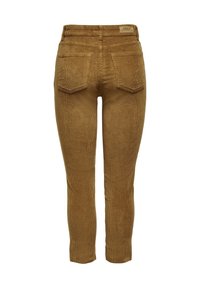Pantalon en velours côtelé marron avec une coupe ajustée, comprenant des poches arrière et une surface texturée. Fermeture à la taille avec une étiquette de marque à l'arrière.