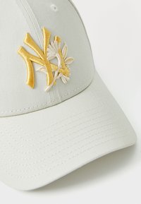Light gray cap made of cotton with a curved visor, featuring a yellow embroidered NY logo and floral accents on the front.
