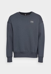 Mörkgrå sweatshirt i en bomullsmix, med rund halsringning, långa ärmar, ribbade muddar och en liten logopatch på bröstet.