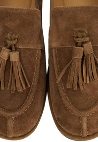 Bruine suède loafers hebben een gestikte ontwerp, opvallende franjes en een zachte textuur, ideaal voor casual gebruik.