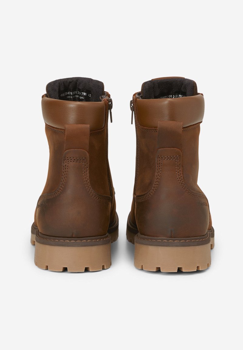 Botas de tobillo de cuero marrón con una superficie ligeramente texturizada, que cuentan con cremalleras laterales, un collar acolchado y una suela de goma marrón resistente.