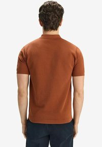Kortärmad polo i texturerad rostfärg, med stickad krage och ribbade ärmslut, med en figurnära design och utan synliga logotyper.