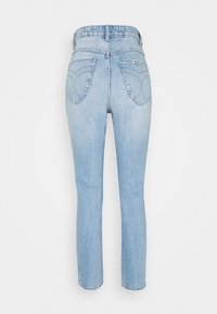 Jean bleu clair taille haute, coupe droite, avec poches arrière et une petite étiquette de marque sur la poche droite, sur fond blanc.