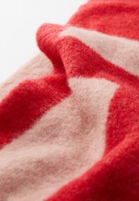 Tessuto di lana a righe rosse e rosa chiaro, che mostra una morbida consistenza e una superficie leggermente pelosa con pieghe e curve delicate.