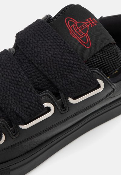 Sort sneaker med strukturerede stofstropper, metaløjer og en sort mesh tunge med et rødt grafisk logo. Holdbar gummisål.