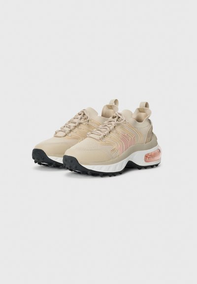 Scarpe sportive beige con tessuto testurizzato, lacci ben visibili e una suola bianca spessa. Presentano un'unità d'aria traslucida di colore rosa e una suola nera con battistrada.