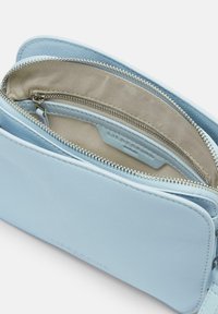 Borse in pelle blu con cerniera argento, caratterizzata da una superficie strutturata e un interno foderato in tessuto, con una tasca aggiuntiva con cerniera.