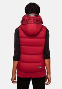 Crvena puffer prsluk s visokim ovratnikom, zatvaranjem na patentni zatvarač i detaljima s logotipom. Ima podstavljene dijelove i pletenu donju traku.