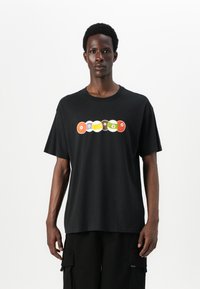 Black cotton t-shirt with short sleeves featuring a colorful graphic of circular designs across the chest. Simple, relaxed fit.