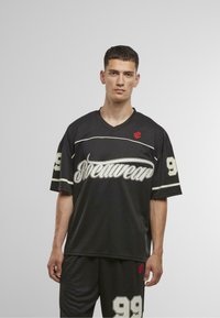 Fekete sportmez fehér kiegészítőkkel, a "Streetwear" felirattal és 99-es számmal. Rövid ujjú és V-nyakú kialakítás, texturált anyagból készült.