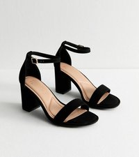 Sandalias de tacón de ante negro con un tacón bloque, diseño de punta abierta y correa de tobillo ajustable. Plantilla suave de color beis con un detalle de costura mínima.