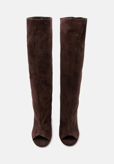 Paire de bottes hautes en daim brun foncé à bouts ouverts, debout sur un fond clair uni.